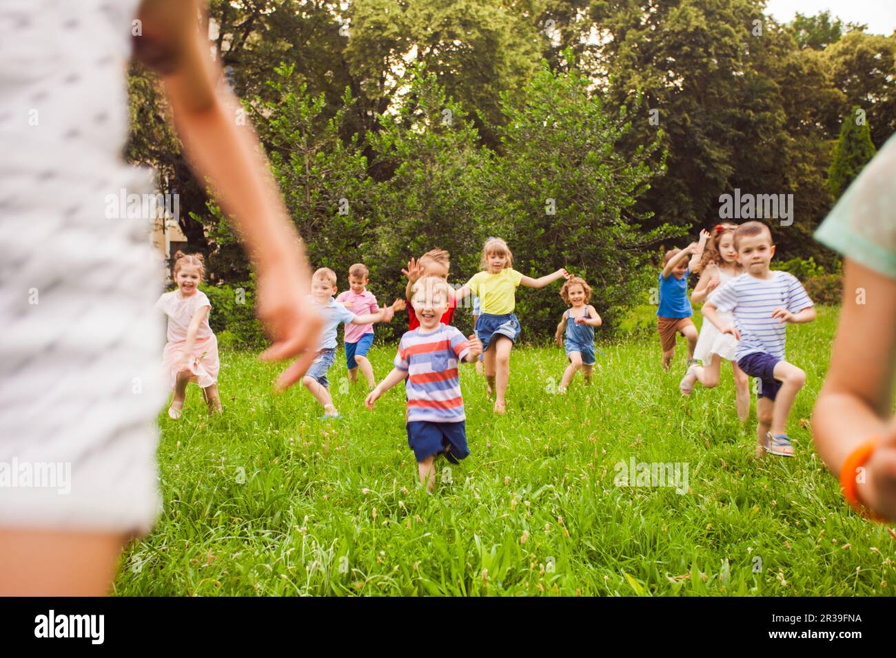 Group of children of boys and girls run in park on green grass Stock Photo