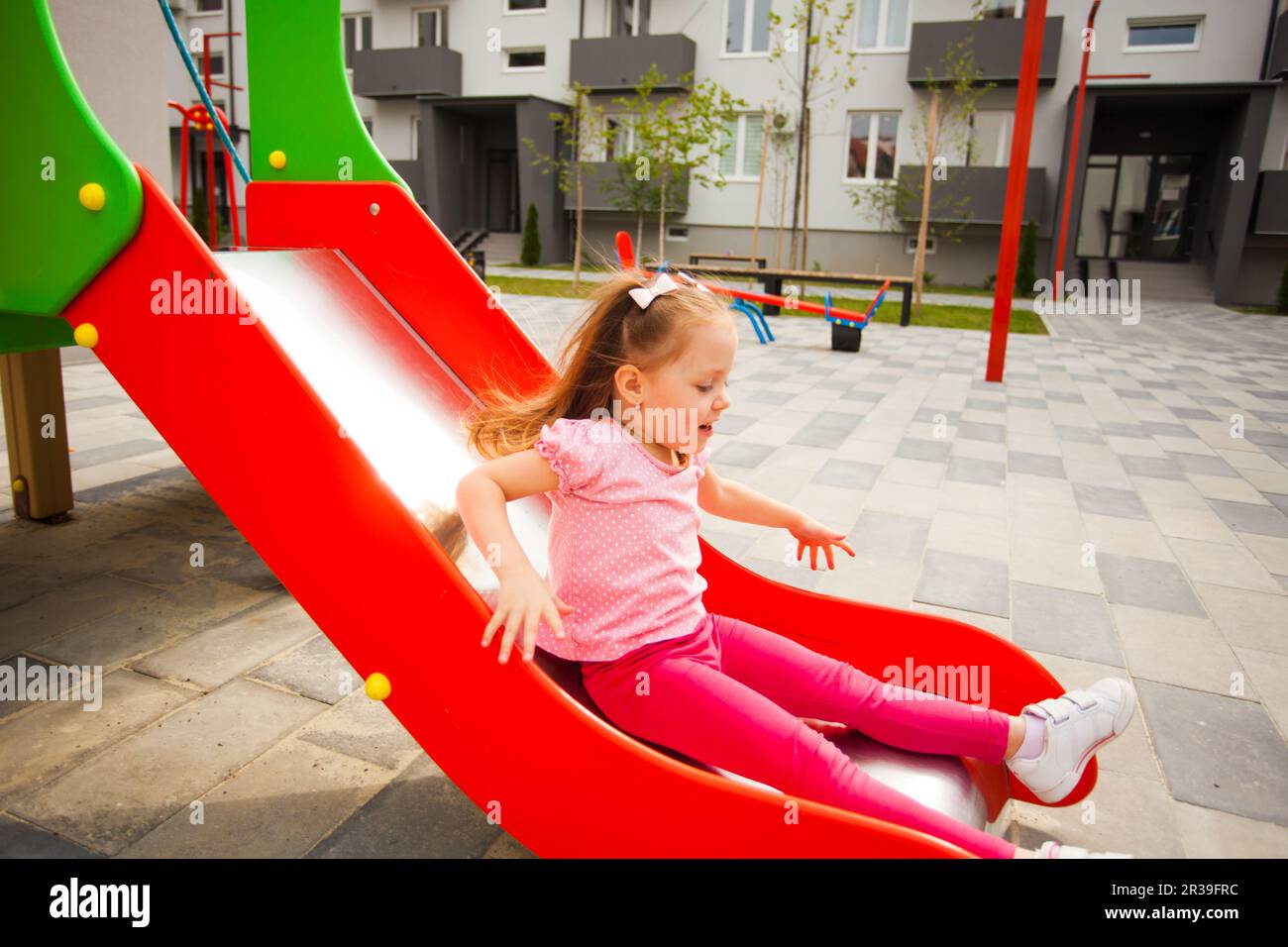 Happy little girl on slide at outdoors playground Stock Photo