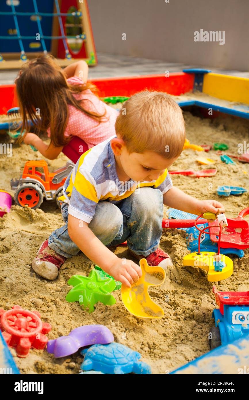 Creative activities for kids. Happy kids playing in sandbox outdoors Stock Photo