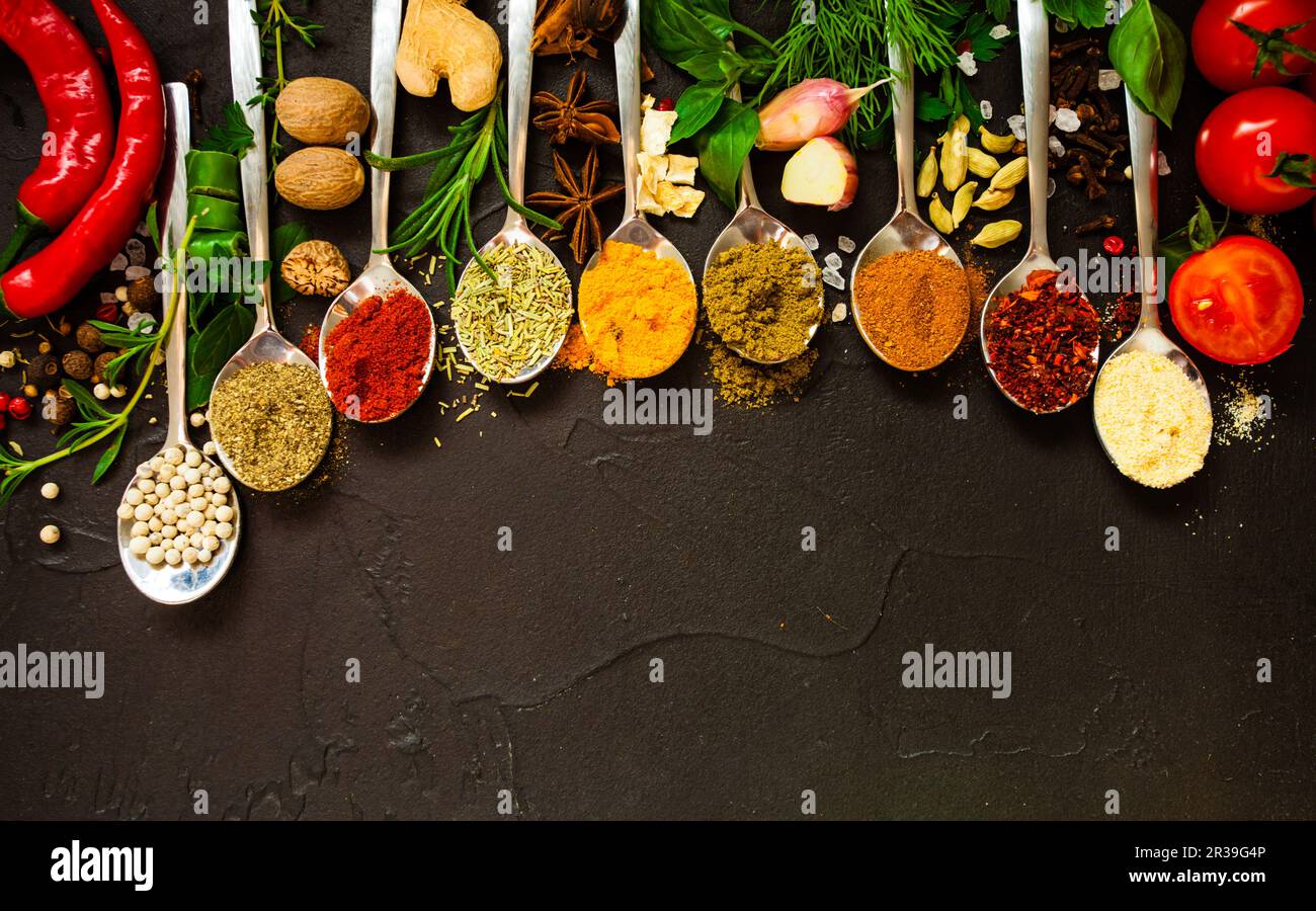 Hand seasoning with a black pepper shaker a fresh salad bowl mixed green  leaves, eggs, black olives and tomato on a wooden table with cutlery.  Nature blurred background. Vertical photography Stock Photo