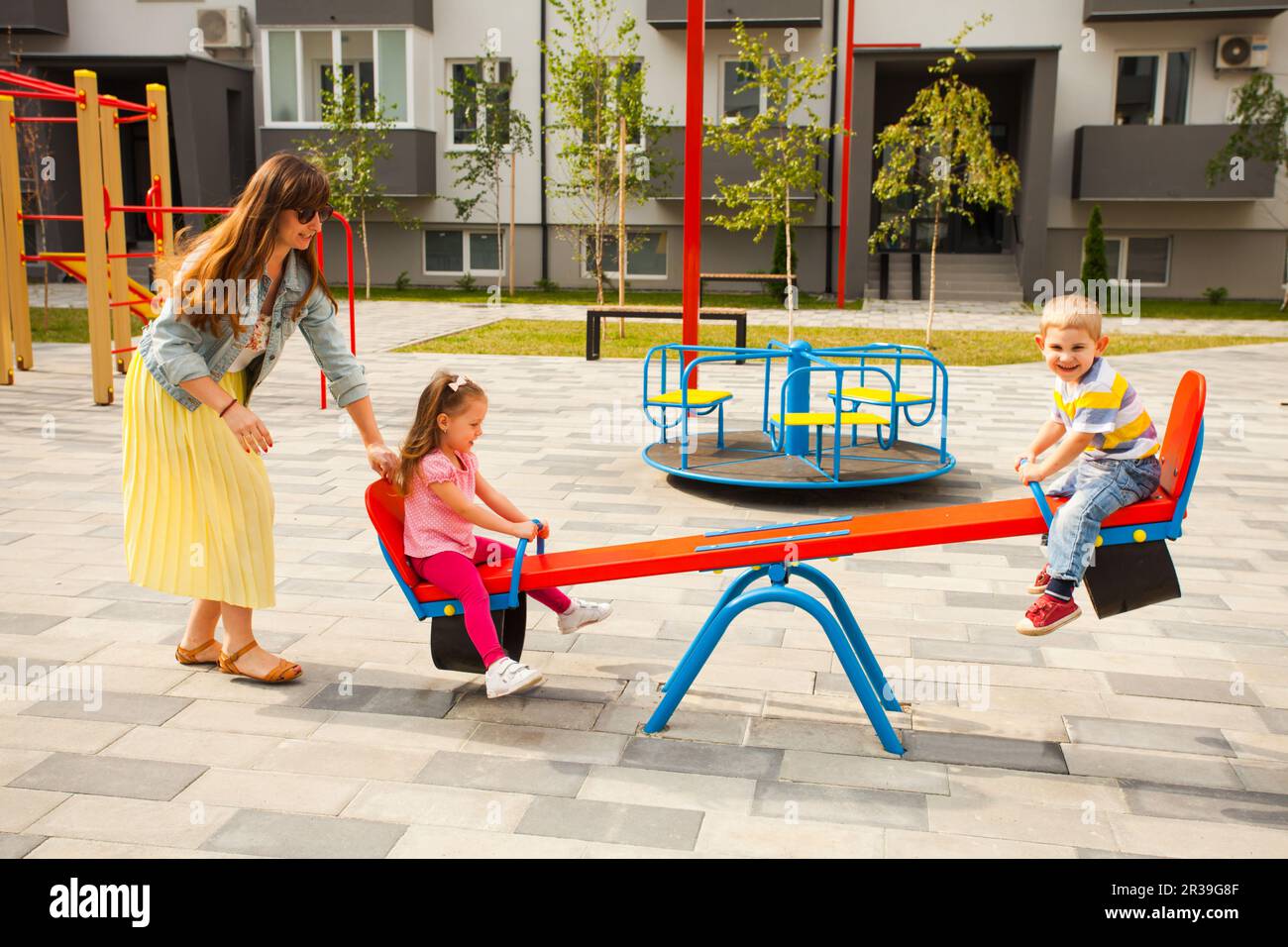 Happy mother playing with children outdoors at playground Stock Photo