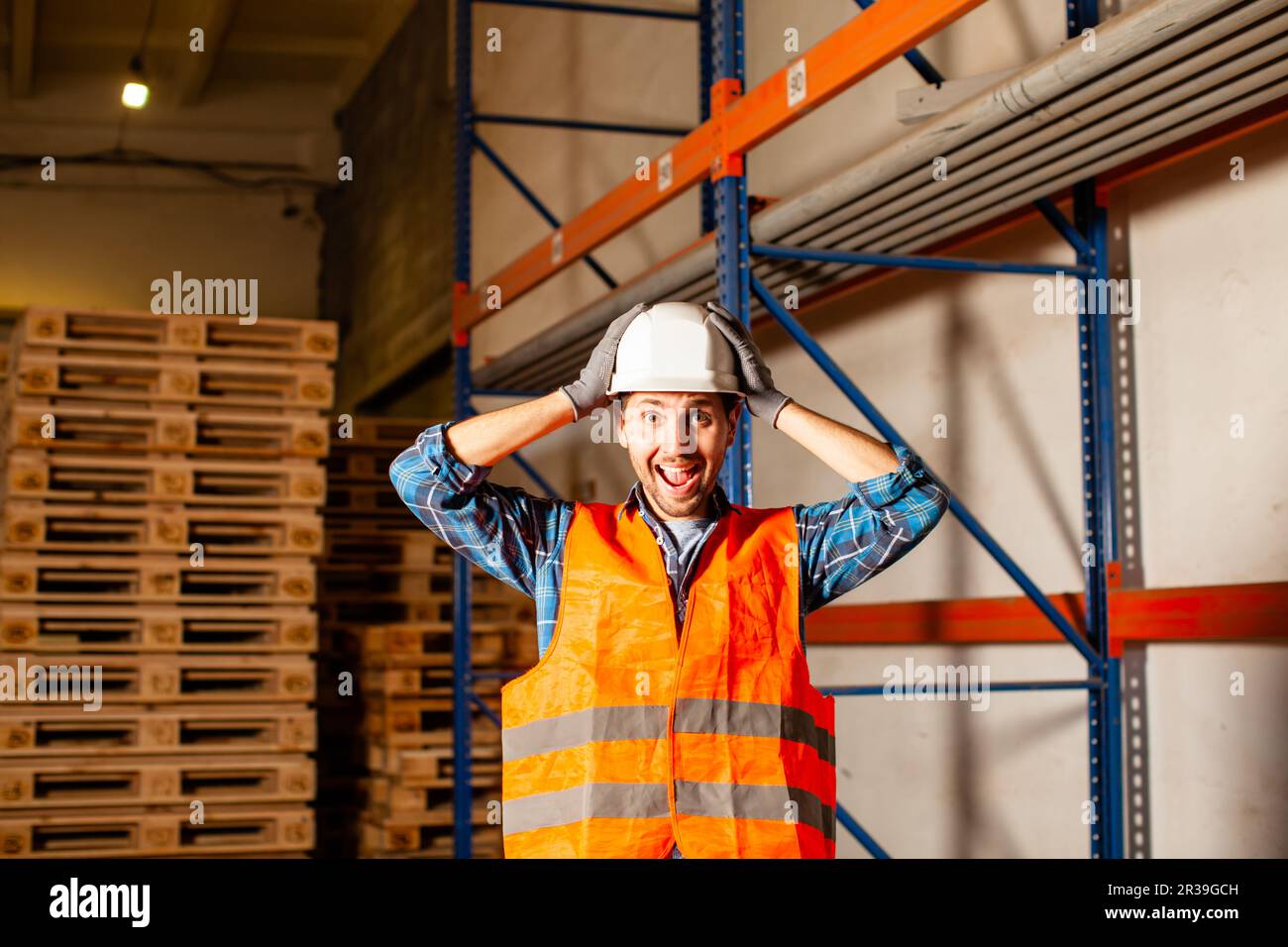 Excited worker touching his protective helmet in the warehouse Stock Photo