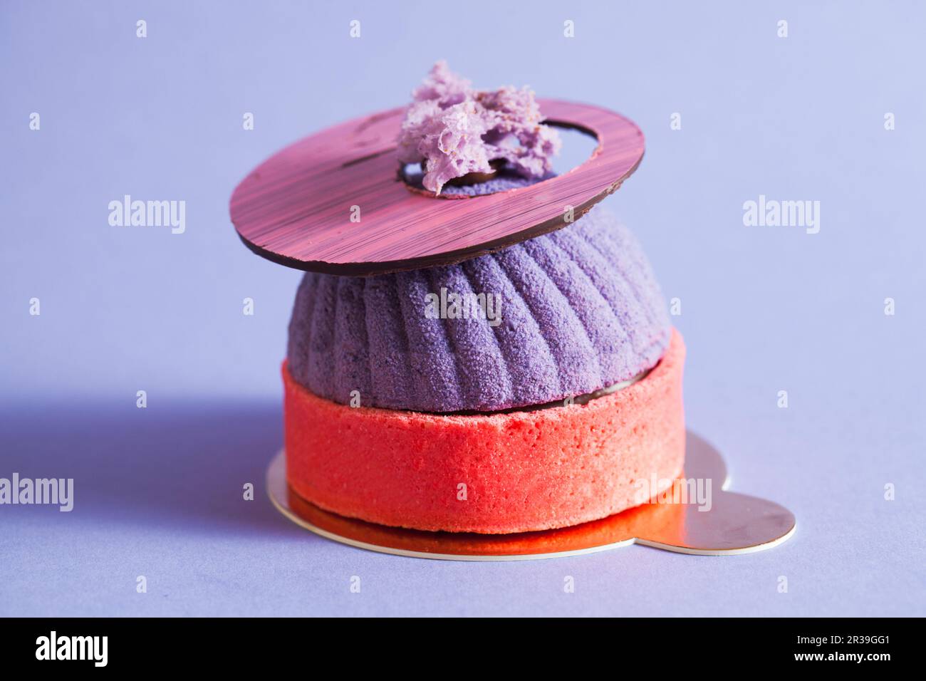 French pastry decorated with purple mirror glaze. Modern european cake with blueberry mousse. Stock Photo