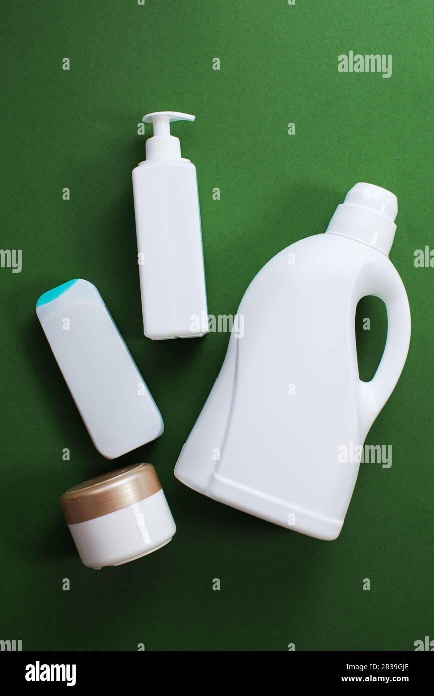 Household chemicals or liquid laundry detergent and other cleaner over green background, top view, flat lay. Stock Photo