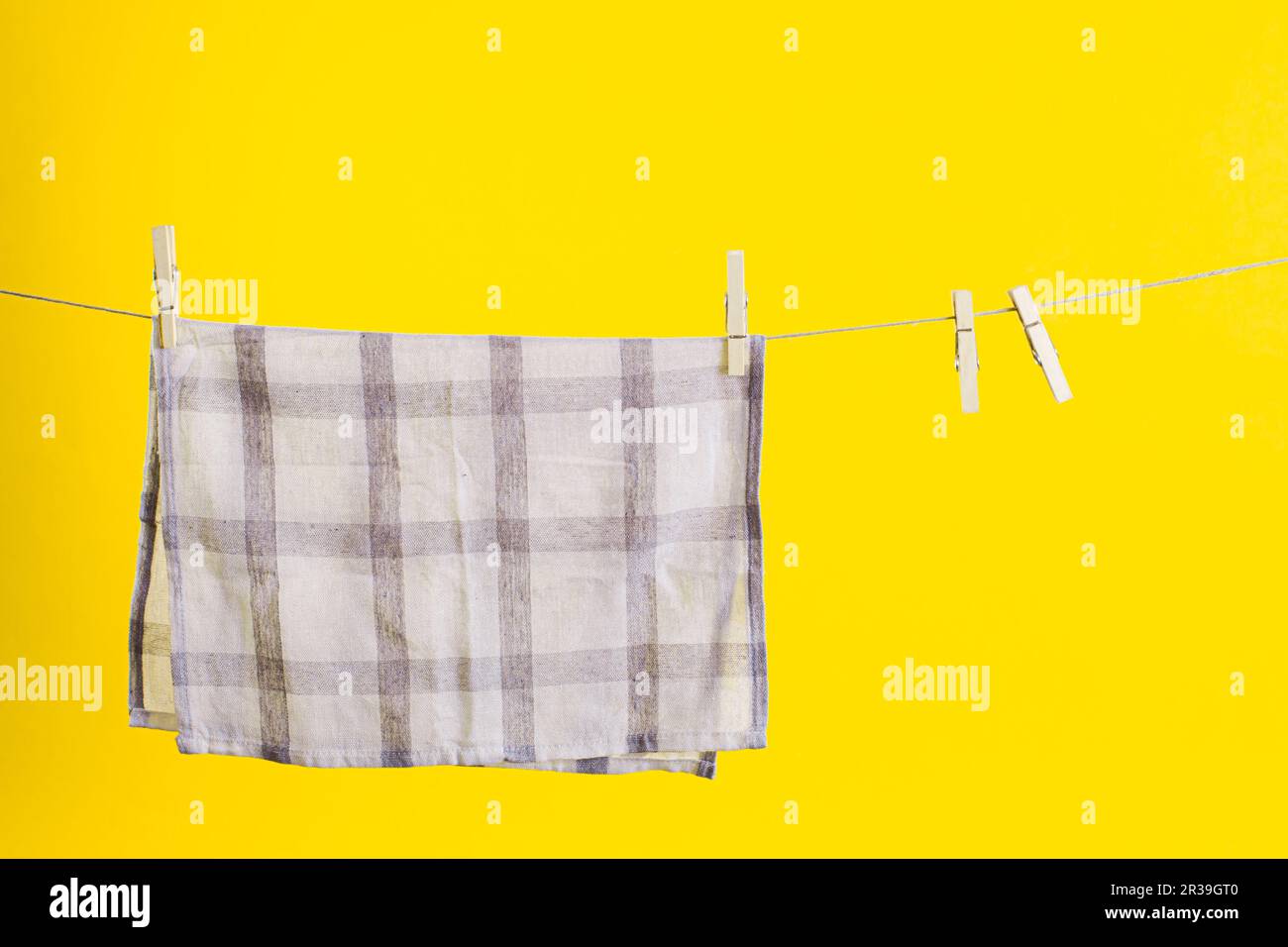 Kitchen towel after washing over yellow background. Mock up for design. Cleaning services Stock Photo