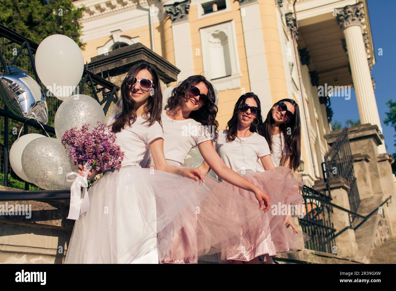 Stylish bridesmaids and bride posing outdoors on summer Stock Photo