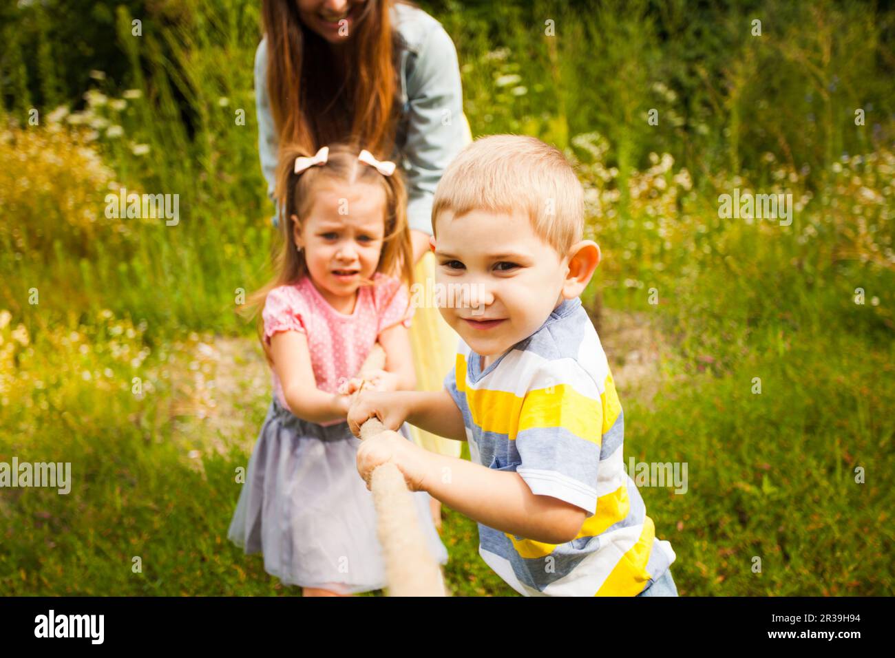 Young family playing tug of war on nature Stock Photo