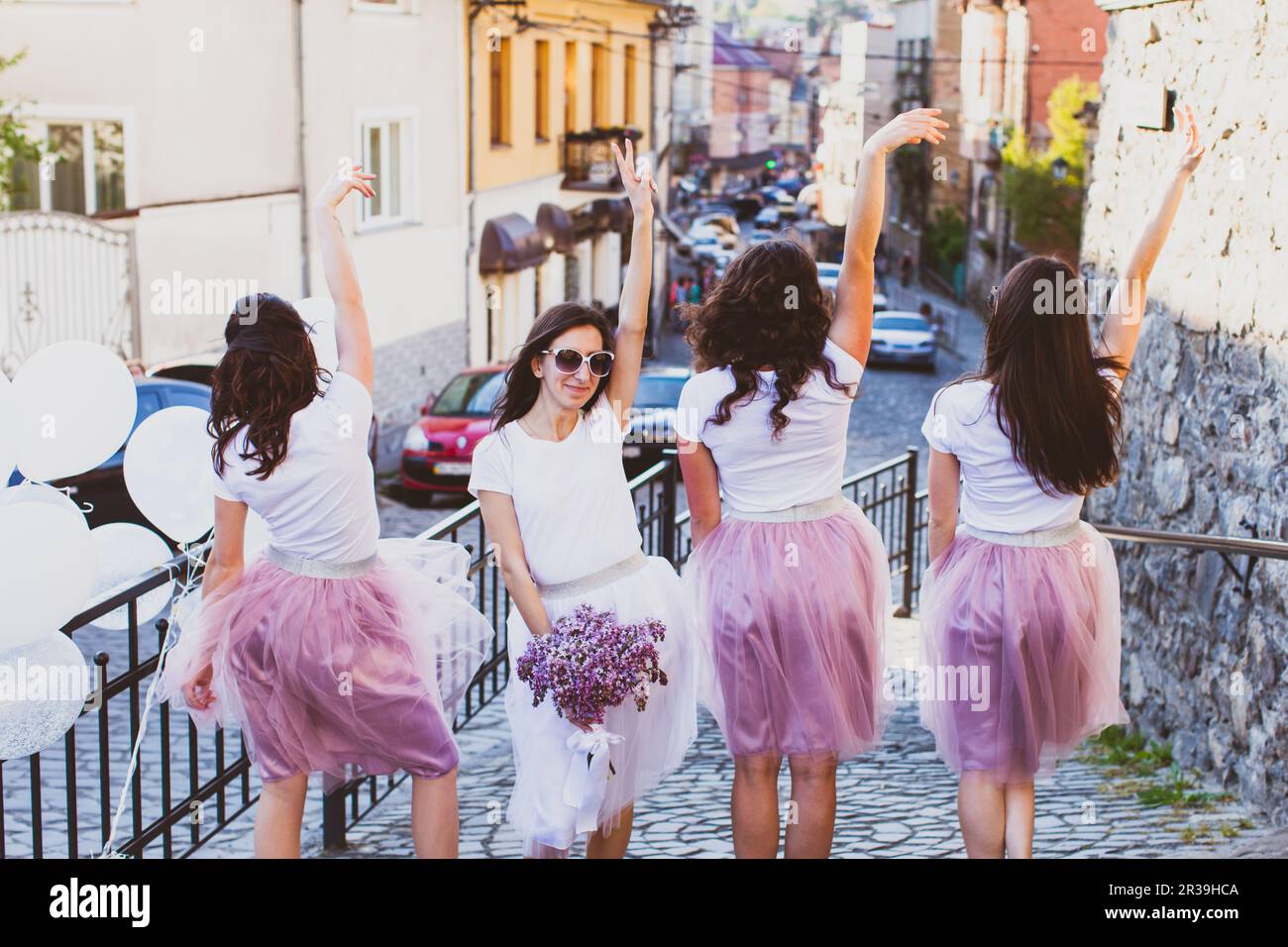 Pretty bride with her friends rasing hands up and posing outdoors Stock Photo