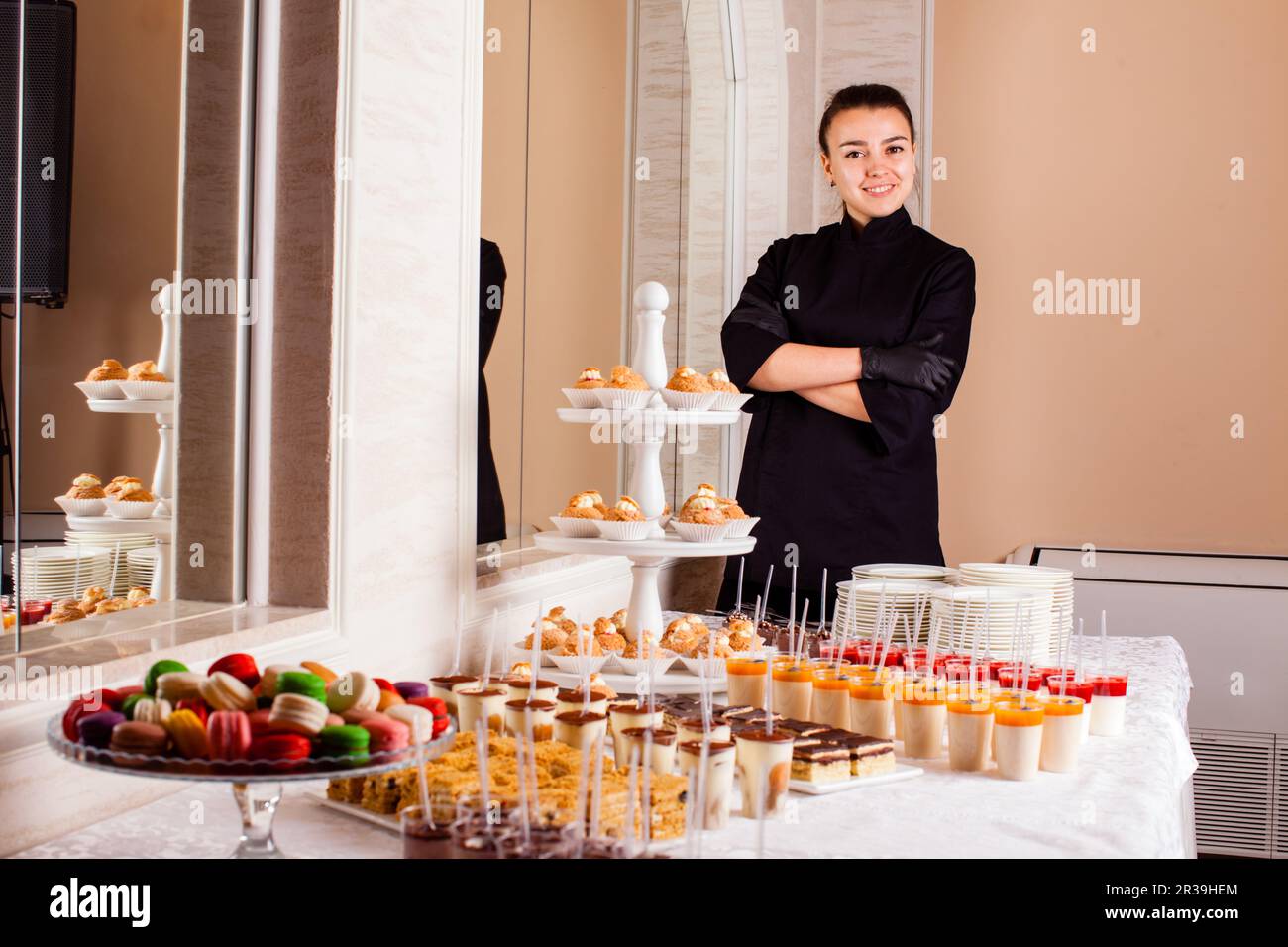 Pastry chef standing near dessert table in restaurant. Woman makes