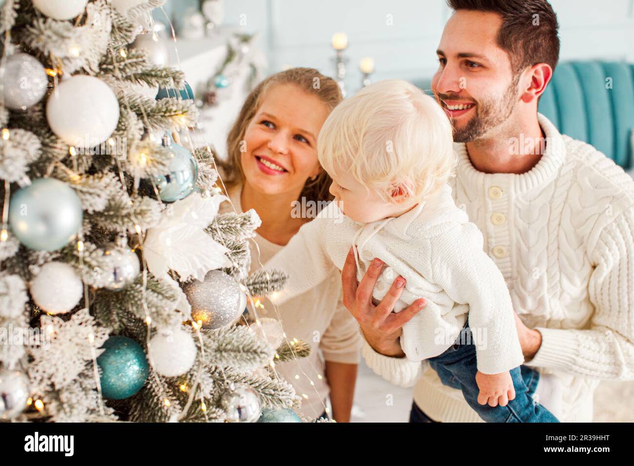 Young happy family with toddler boy near Christmas tree Stock Photo