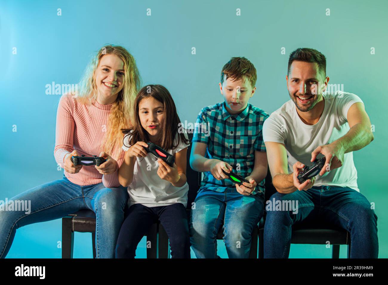 Young cheerful parents and kids playing video game together Stock Photo