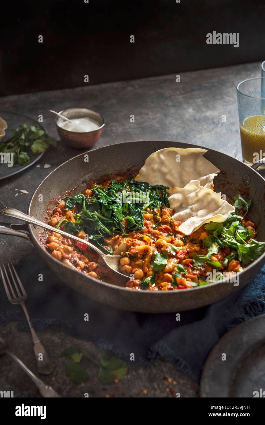 Vegeterian chickpea and spinach curry with coriander and poppadoms Stock Photo