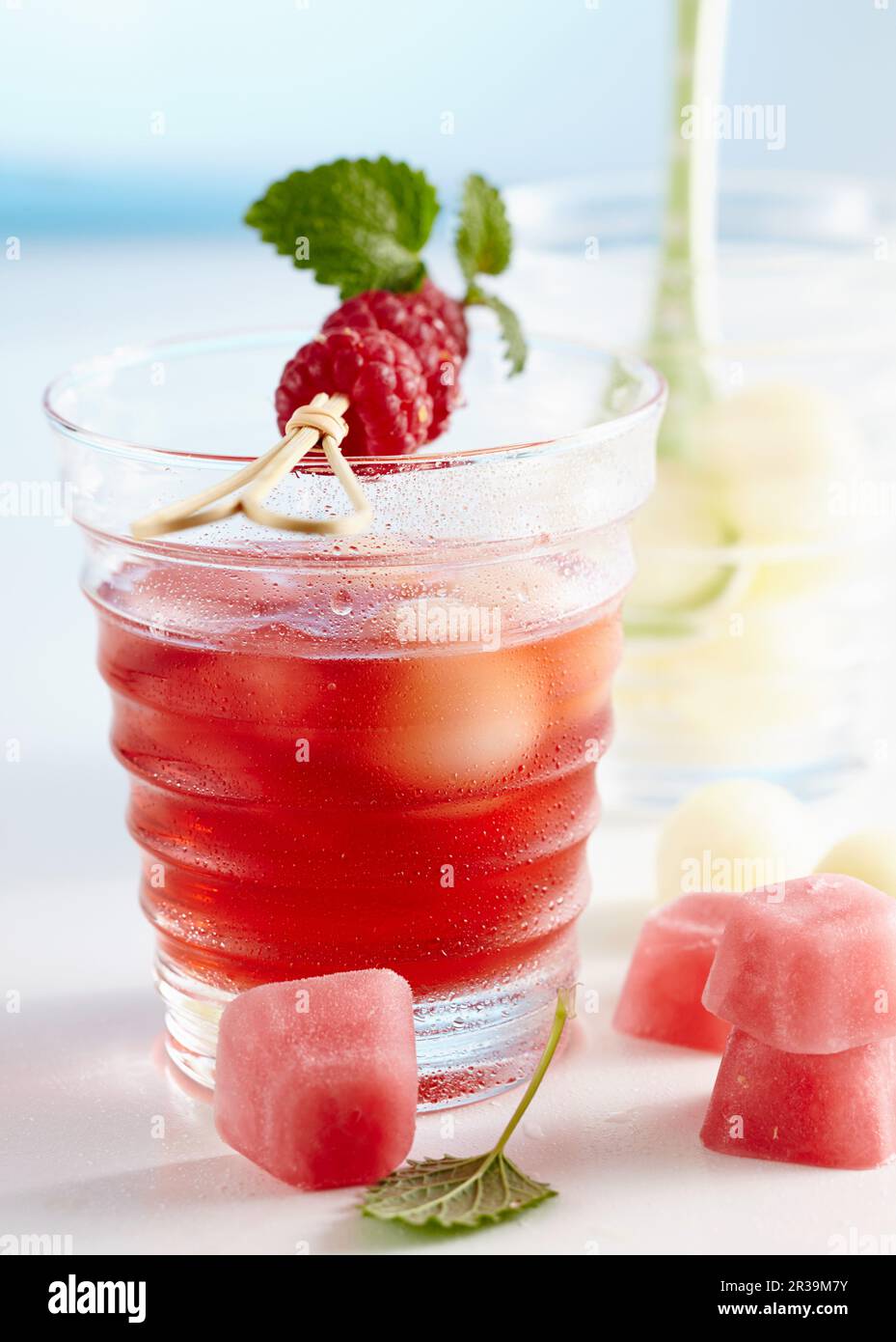 Non-alcoholic punch with raspberries and honey dew melon served with pink ice cubes Stock Photo