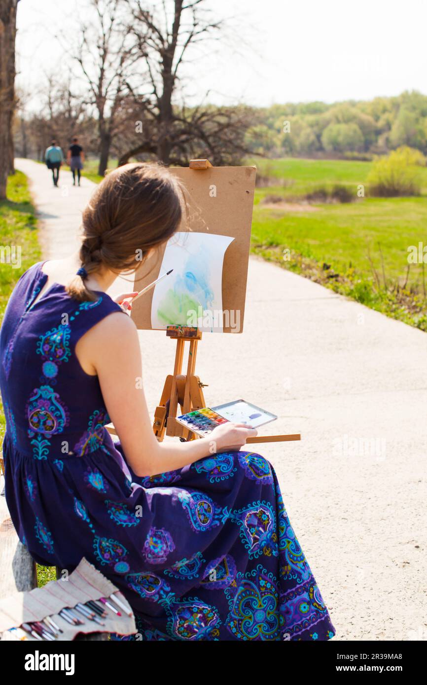 Young female artist working on painting outdoors. Stock Photo