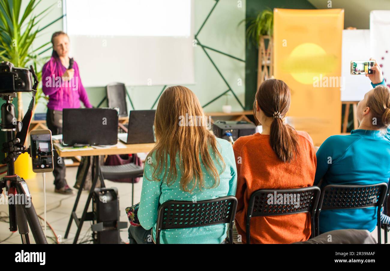 Phone Camera Inlecture Image Female speaker giving presentation at workshop. Recording a lecture on ...