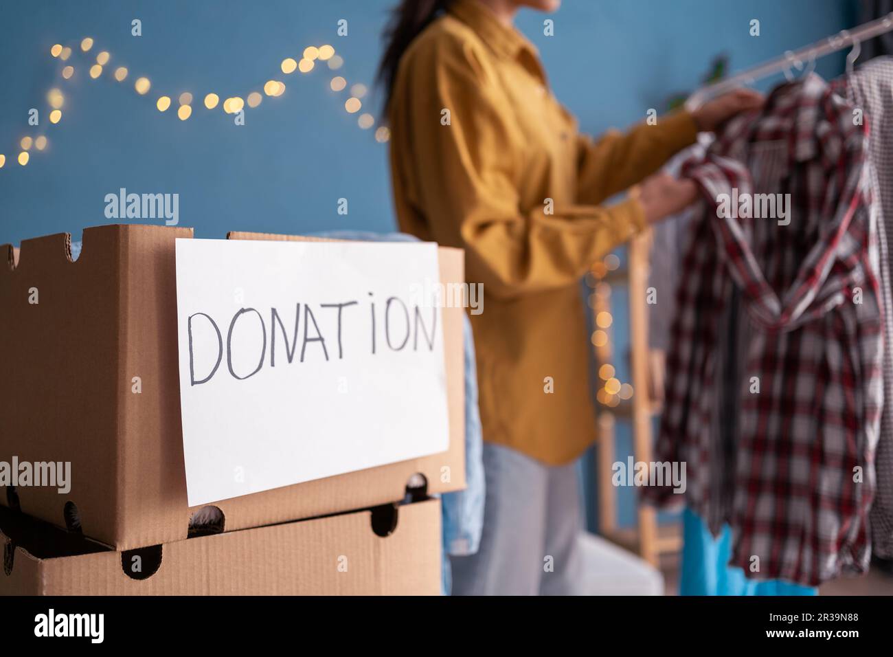 Woman packing clothing donation box on home room background Stock Photo