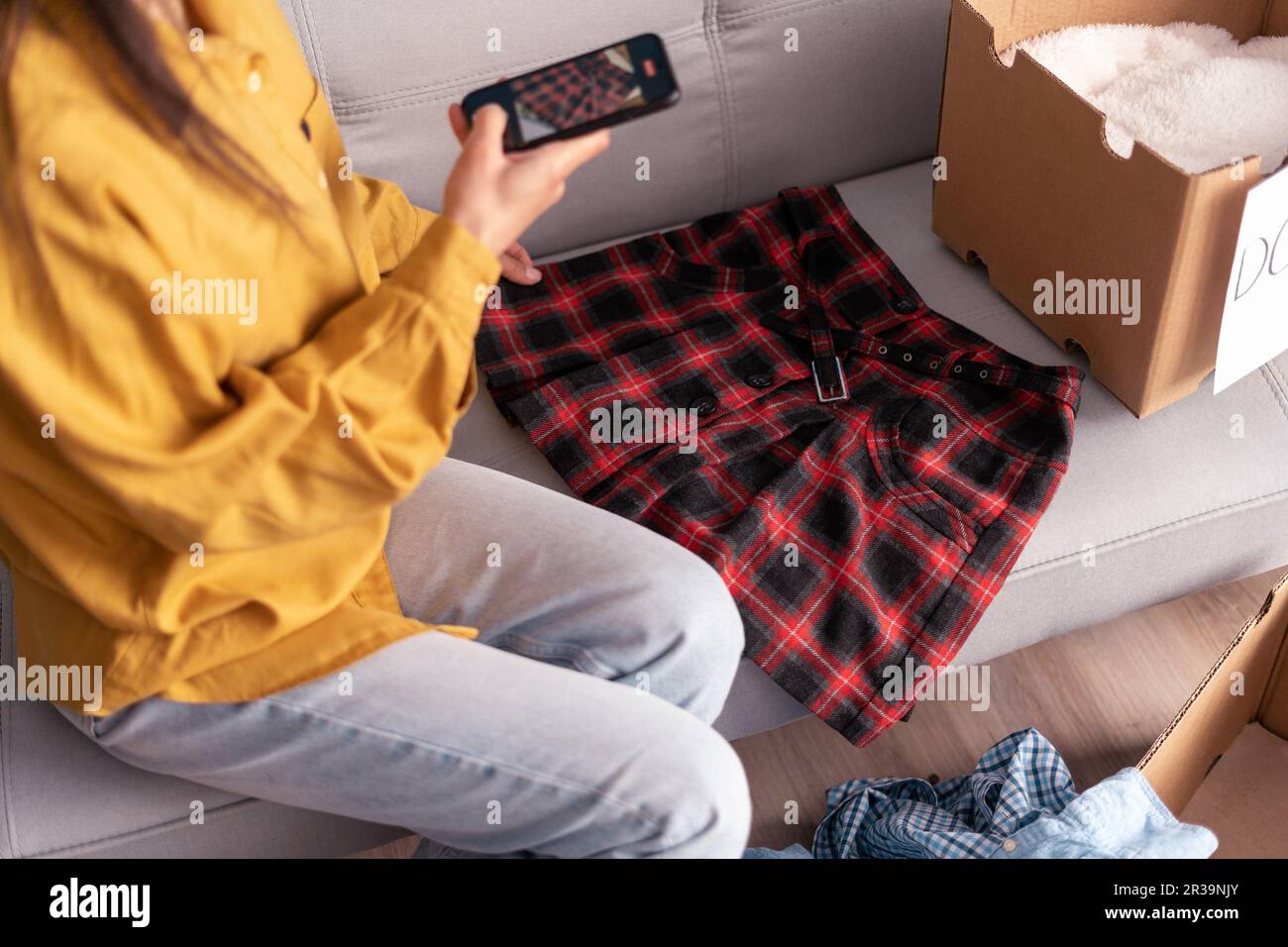 Woman taking photo of skirt at home on smartphone camera for post to sell online on internet market website, selling online ecommerce Stock Photo