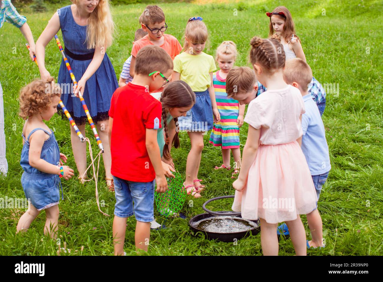 Children learning to make big soap bubbles outdoors Stock Photo