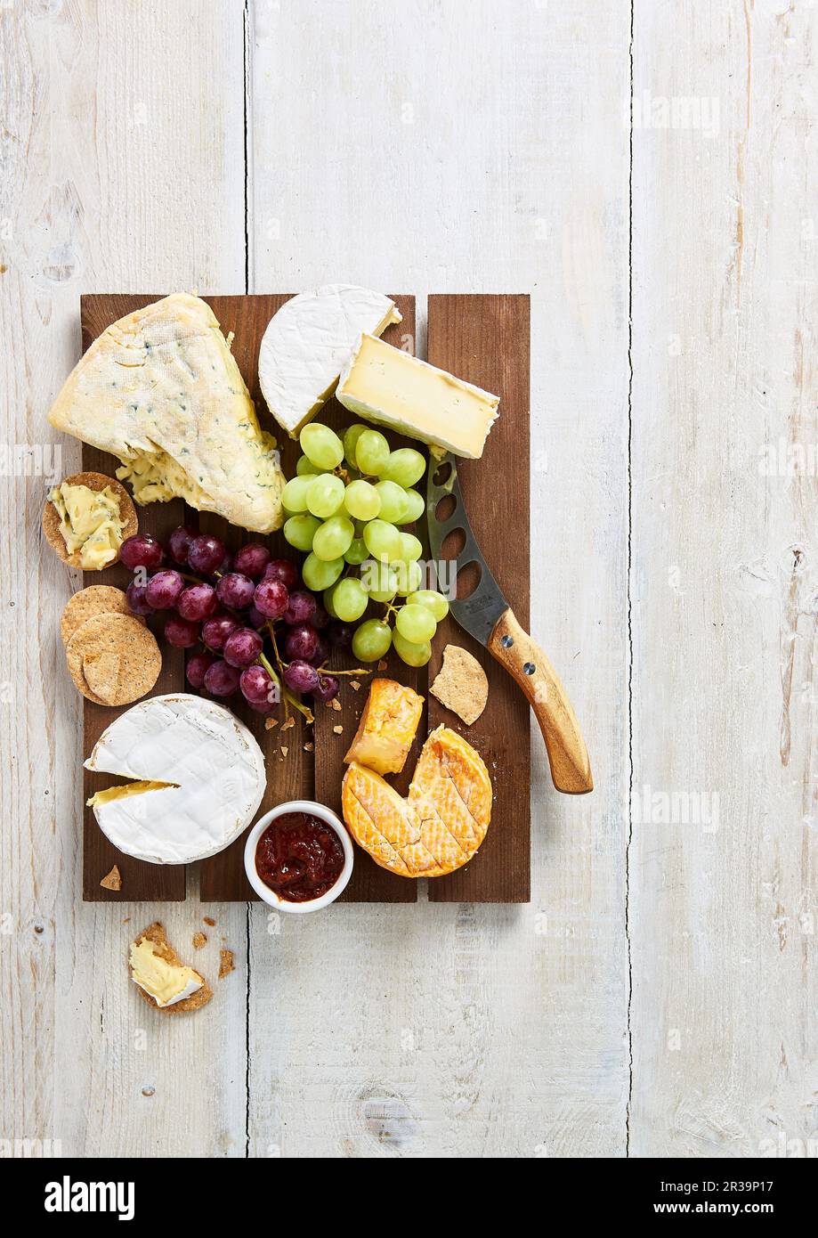 Selection of soft cheeses with biscuits, grapes and chutney on a brown