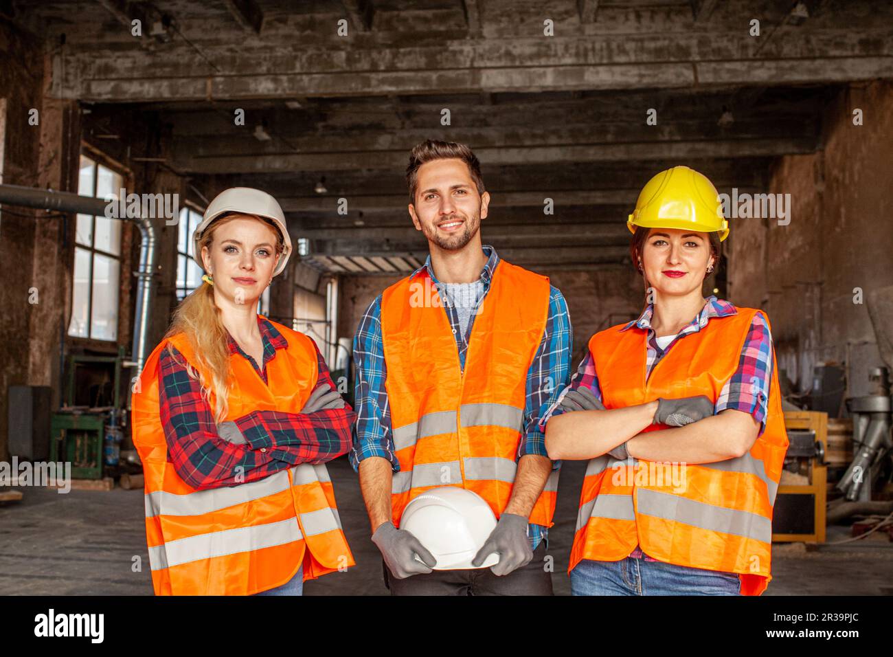 Factory workers in orange protective vests during work Stock Photo