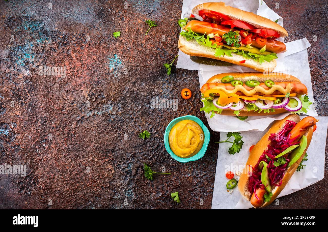 Variety of delicious hot dogs with vegetables and sauces on a vintage serving tray. View from above. Stock Photo