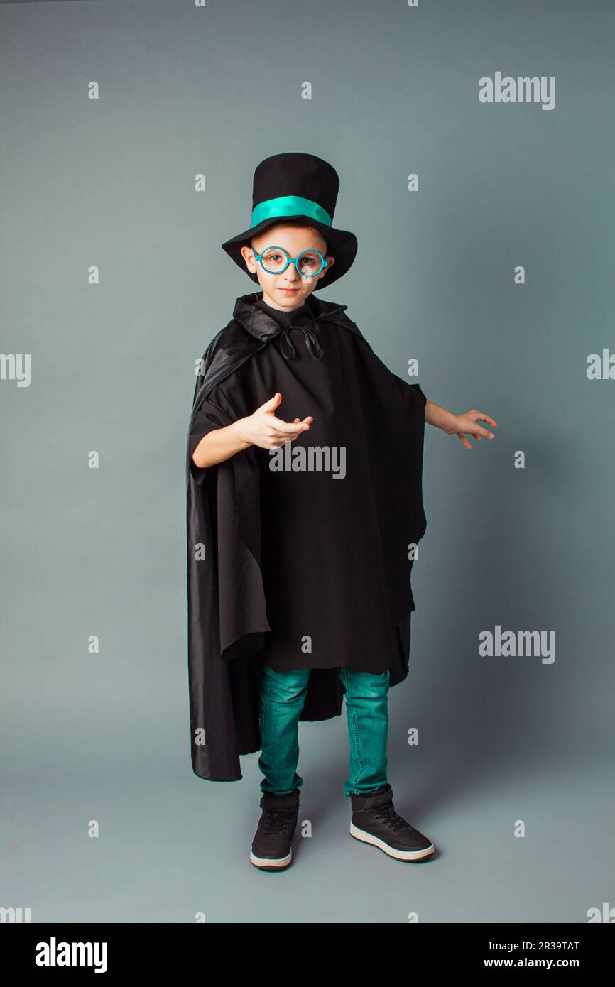 Young magician performing a trick. Little boy wearing top-hat and black magician cloak. Stock Photo