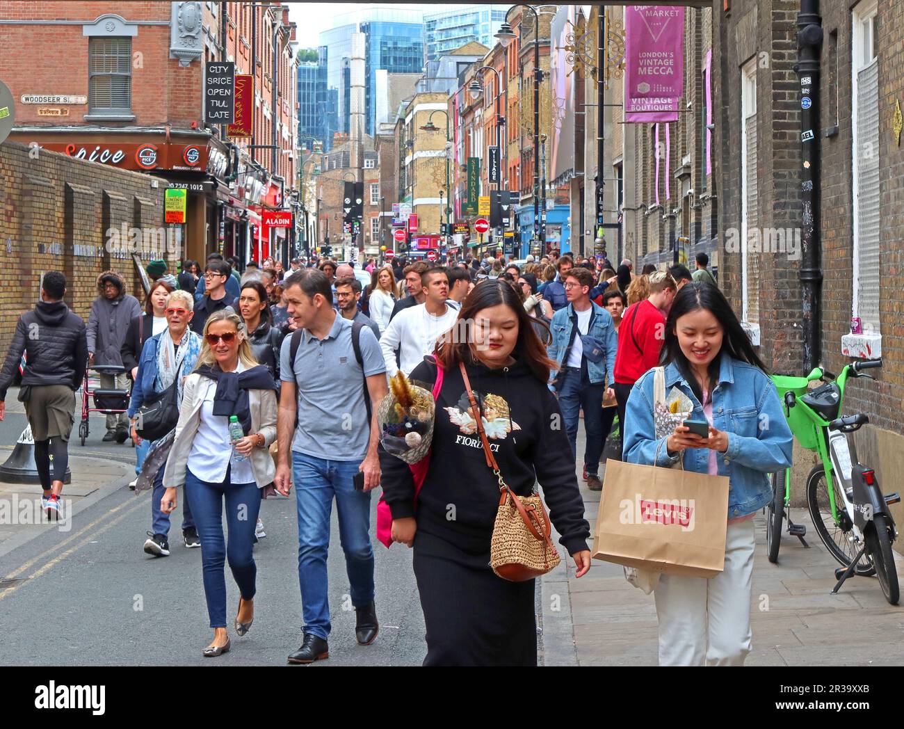 Crowded street with tourists on a busy Brick Lane, London, GB, E1 6QL, looking east towards mosque and Aldgate East Stock Photo