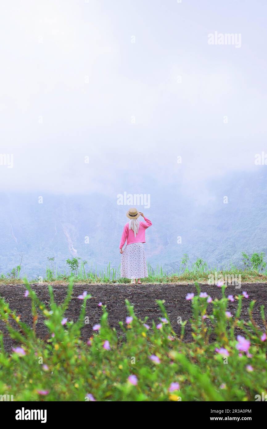A female traveler sits enjoying the beauty of nature from above the mountains Stock Photo