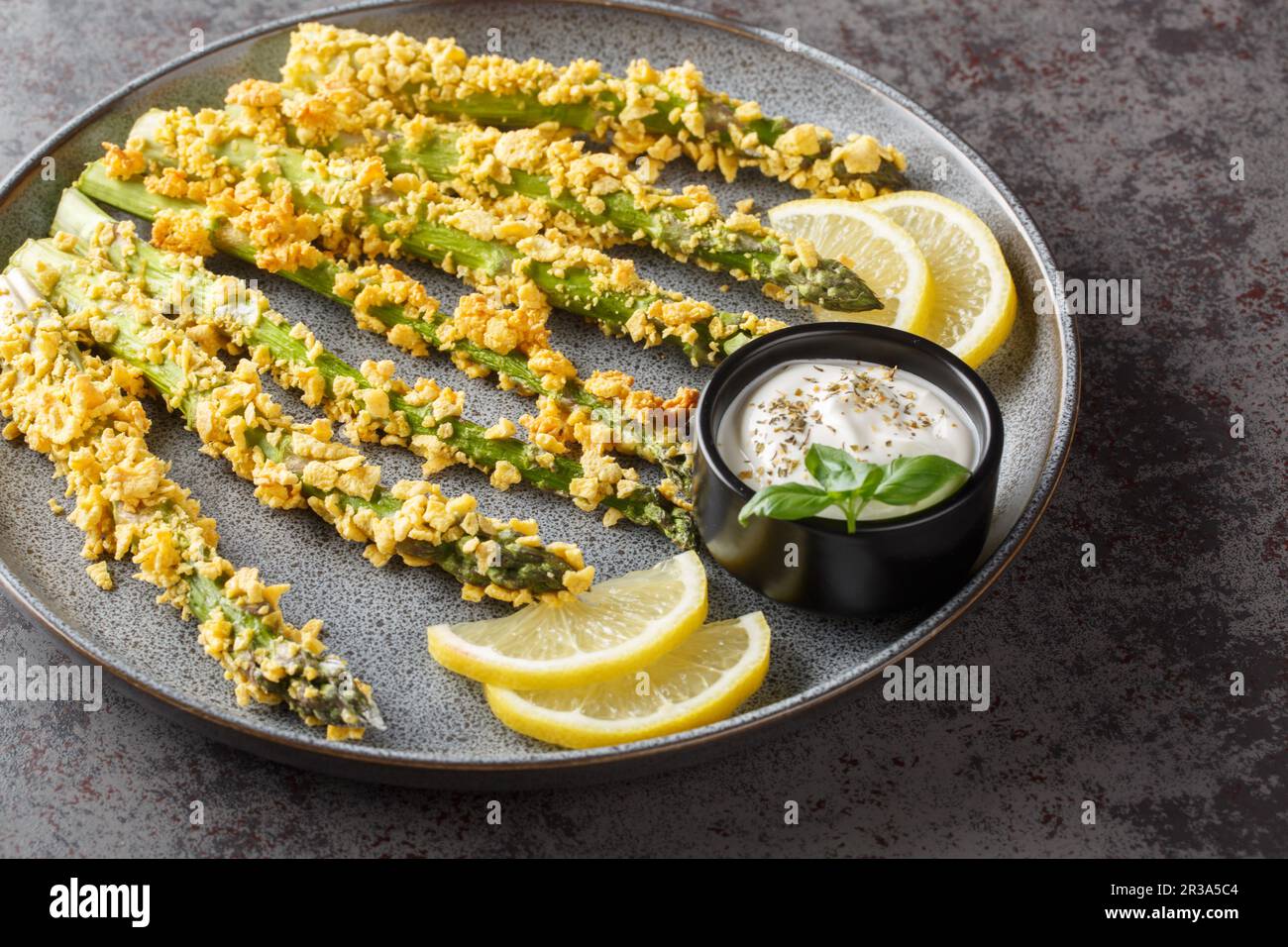 Keto Baked Parmesan Asparagus Fries with panko close-up on a plate on a table. Horizontal Stock Photo