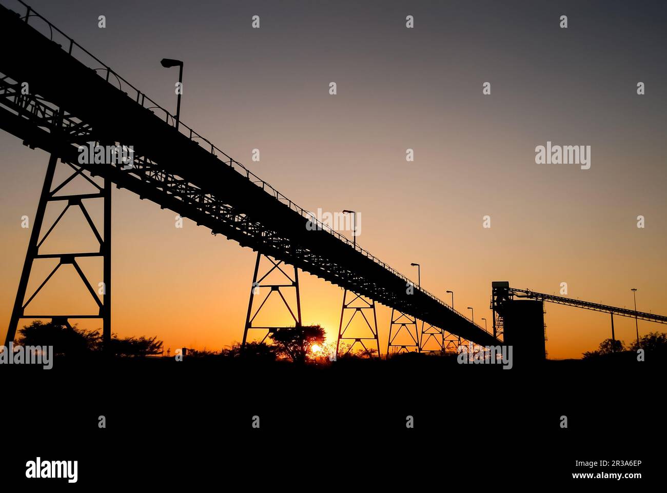 Silhouette of mining silo and conveyor belts at sunset Stock Photo