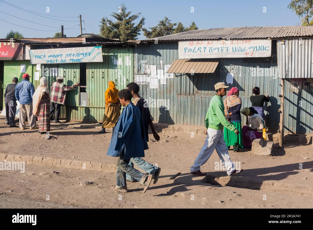 Informal shop owners opening their stores for business as people walk by on a busy side street Stock Photo