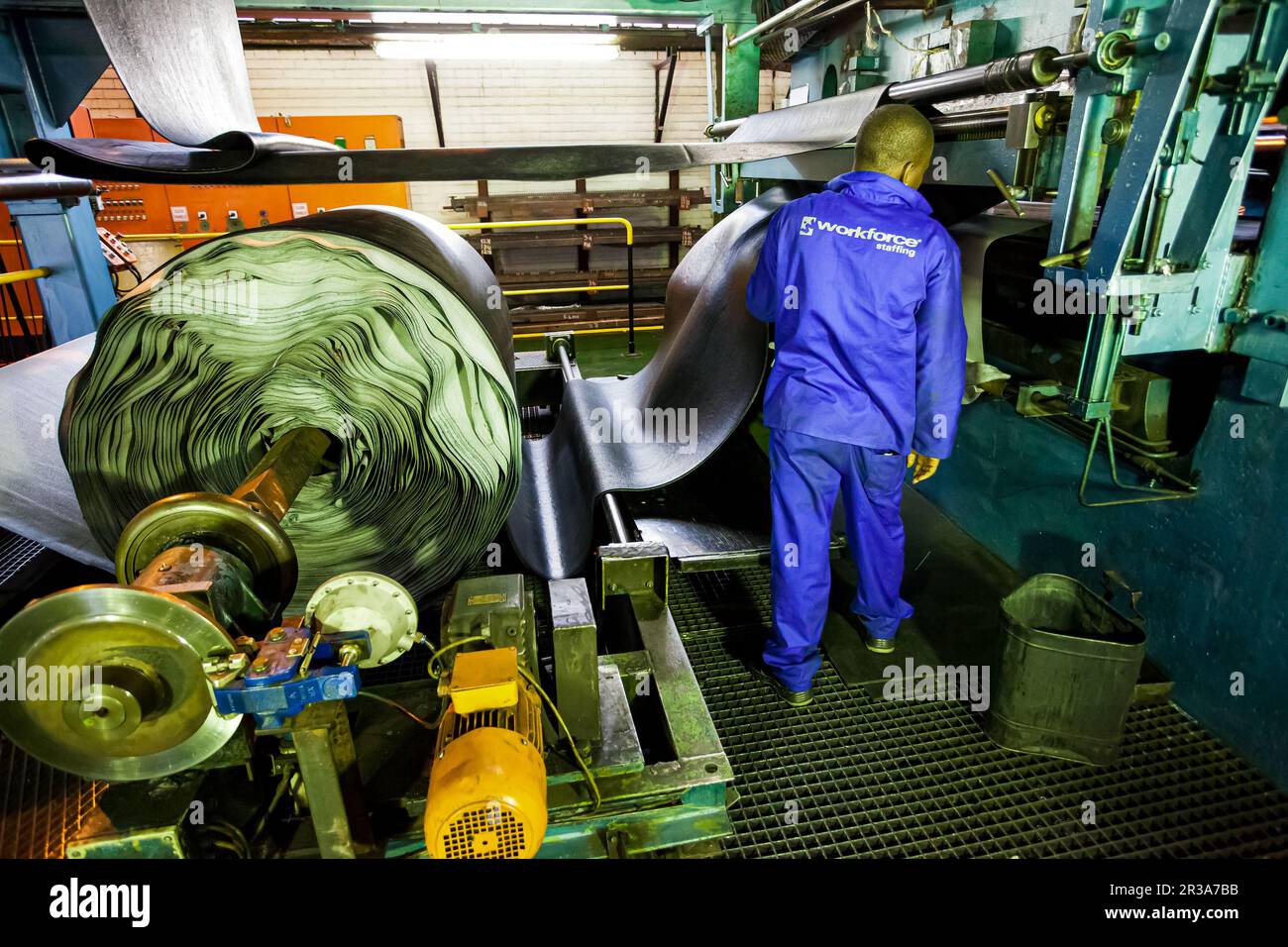 Johannesburg, South Africa October 16, 2012 African factory worker checking a roll of rubber