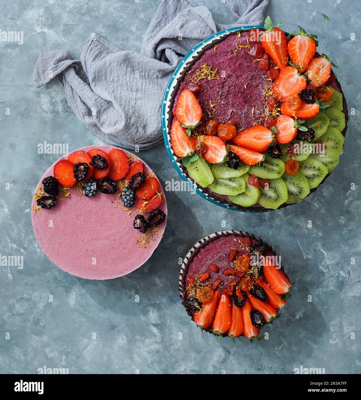 Vegan raw cheesecakes, top view with blueberry, cherry, matcha tea, orange, cashew cream, coconut butter and coconut milk, and base made of almonds, d Stock Photo