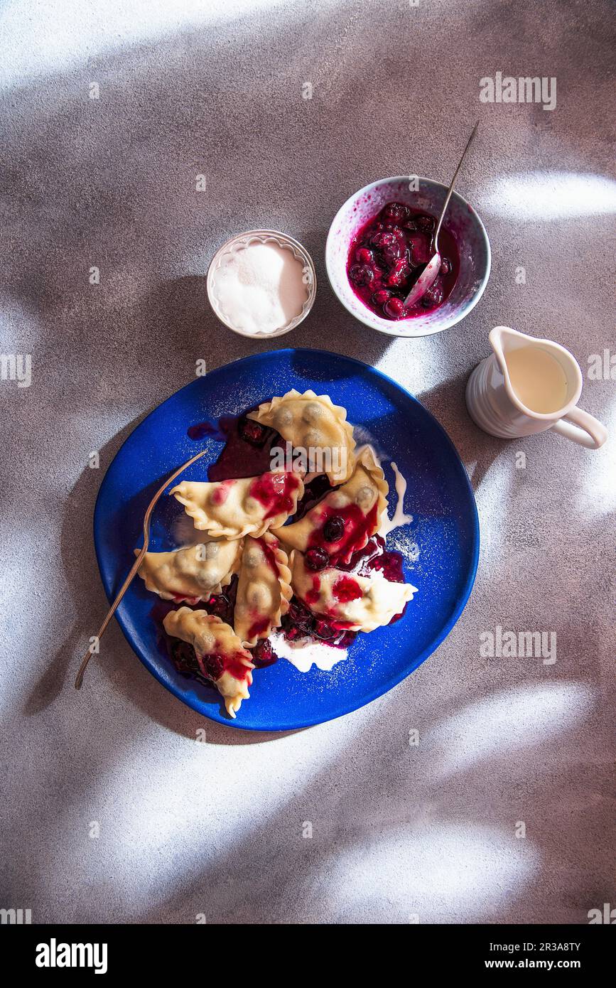 Ravioli with blueberries, bluberry sauce, cream and sugar, view from above Stock Photo