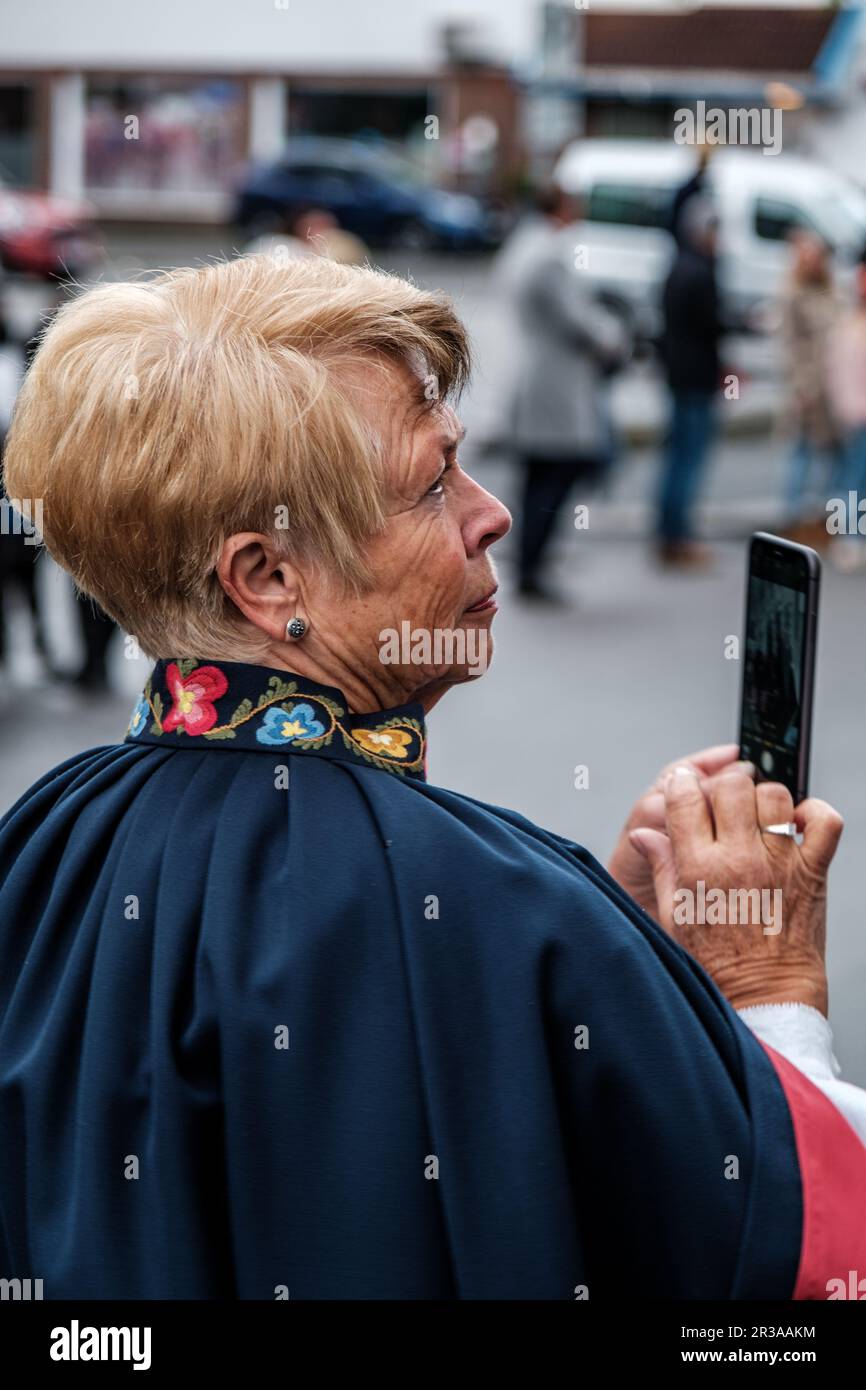 Sandnes, Norway, May 17 2023, Senior Woman Wearing Traditional Norwegian Dress Using A Mobile Phone Stock Photo