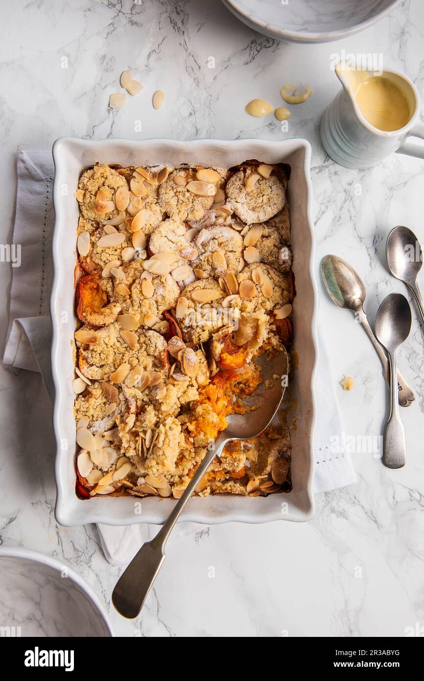 Apricot and almond crumble with custard Stock Photo Alamy