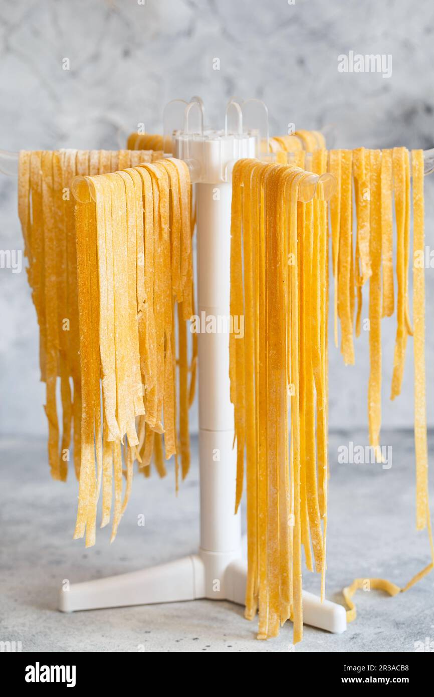 Homemade Italian tagliatelle hanging on a pasta drying rack. Fresh
