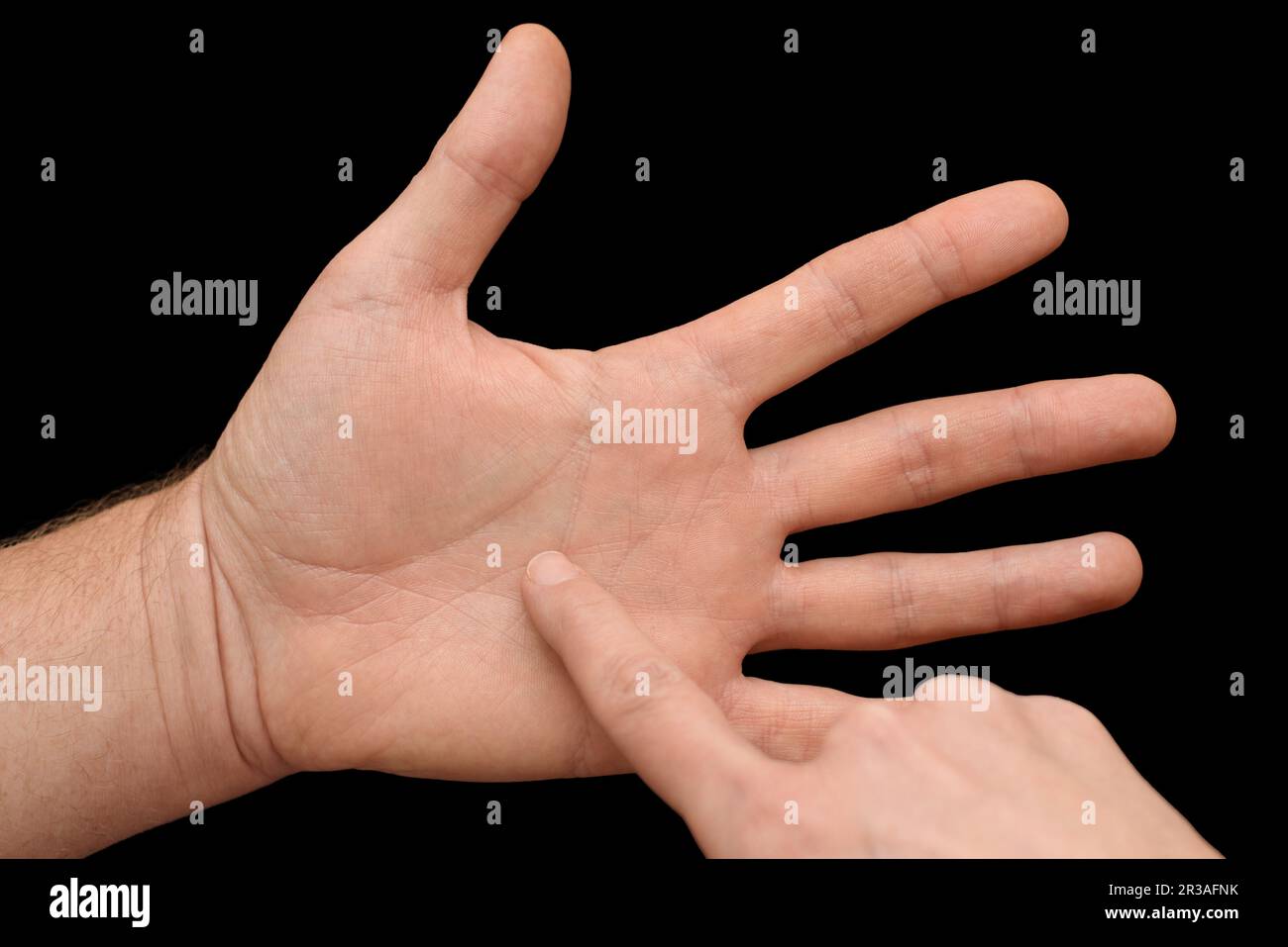 Chiromancer reading the lines on man's palm isolated on black background. The concept of palmistry and fortune-telling. Closeup Stock Photo