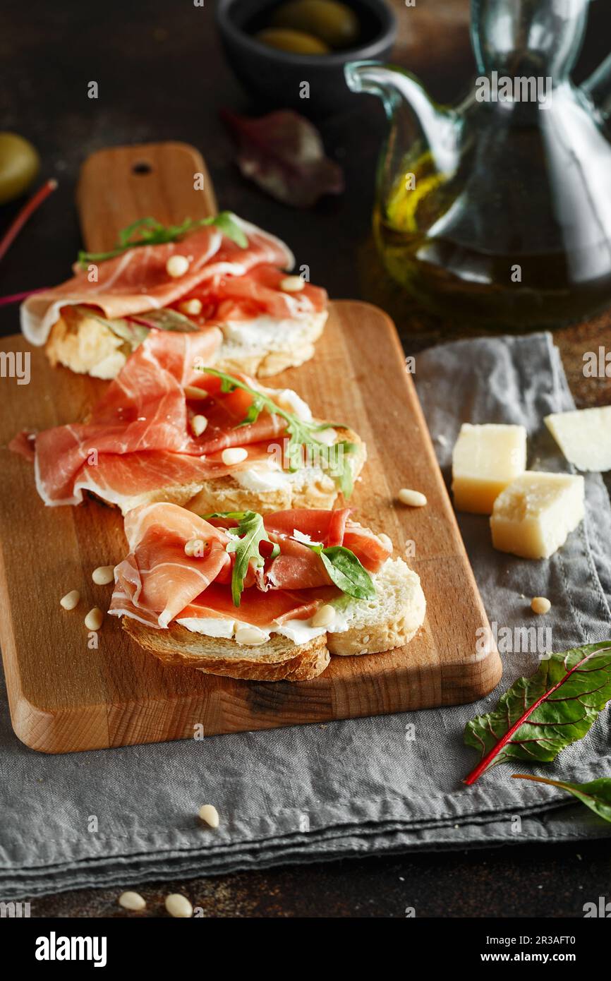 Traditional parma cured ham antipasto. Bruschetta set with Parma Ham and Parmesan Cheese. Small sand Stock Photo