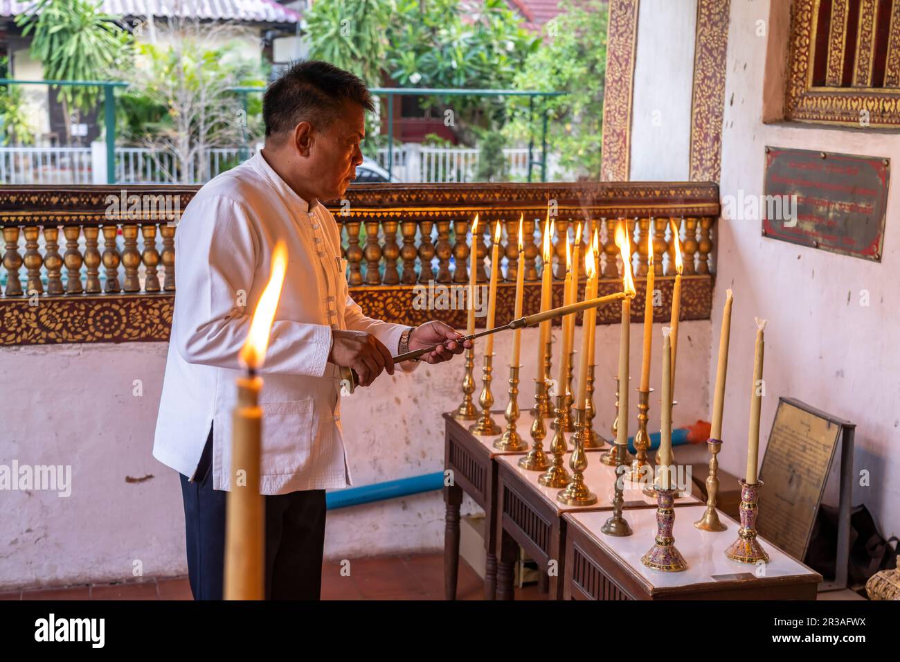 In der  buddhistischen Tempelanlage Wat Phra Singh werden Kerzen angezündet, Chiang Mai, Thailand, Asien   |  Man lighting candles at the buddhist tem Stock Photo