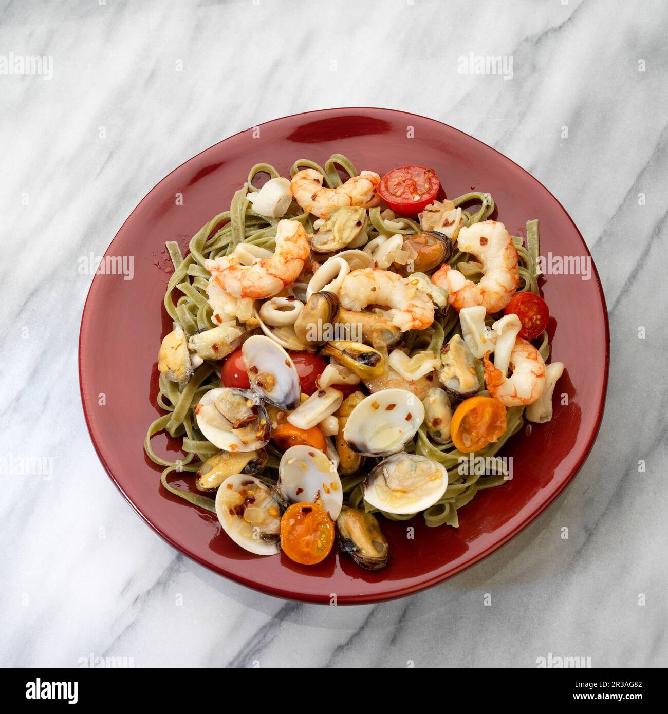Mediteranian seafood, white wine, shrimp, mussels, clams, calamari, tomatoes in plate on white Stock Photo