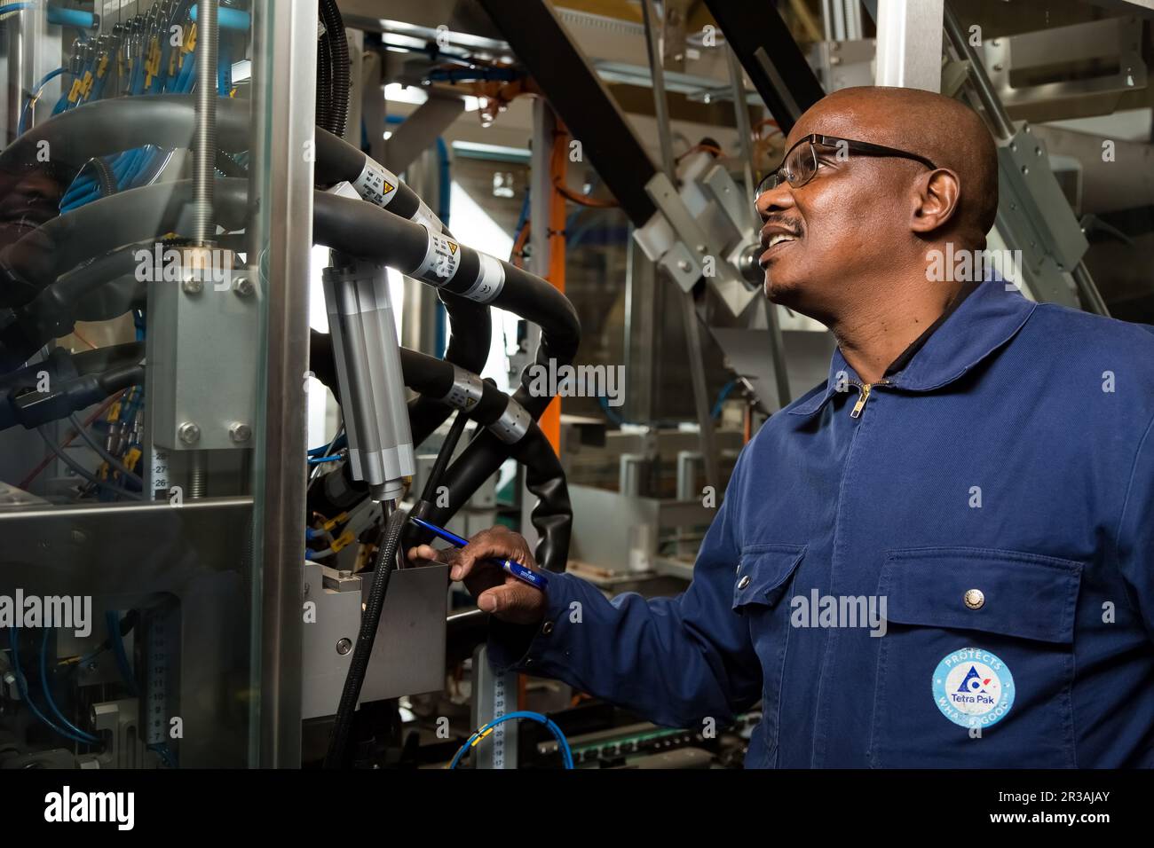 Black African male supervisor checking a machine on a packaging plant
