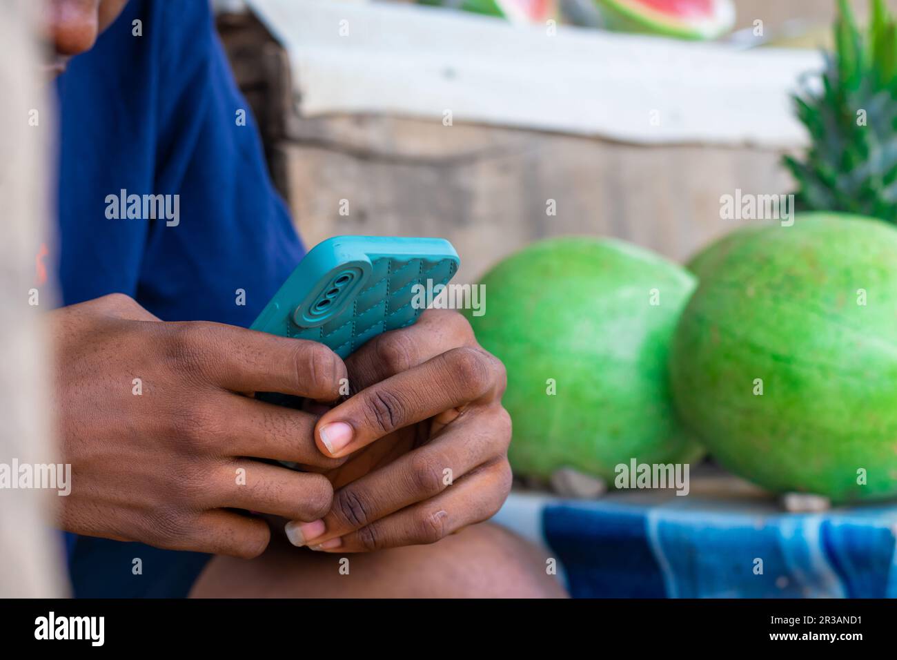 copy space image of Young black man using his mobile phone, isolated in a local market Stock Photo