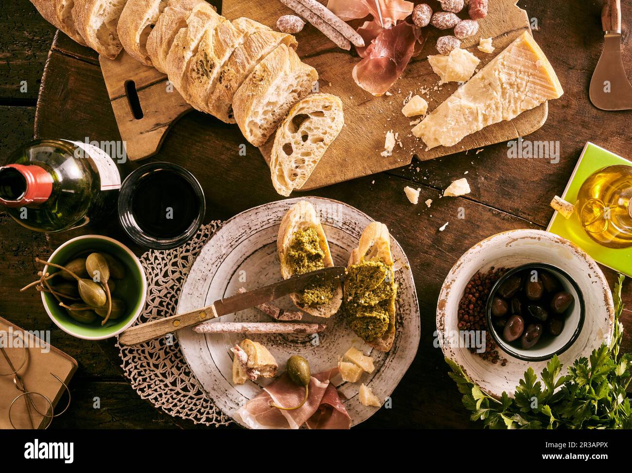 Bruschetta with pesto, mini salami, olives, Parmesan, olive oil, giant capers and red wine Stock Photo