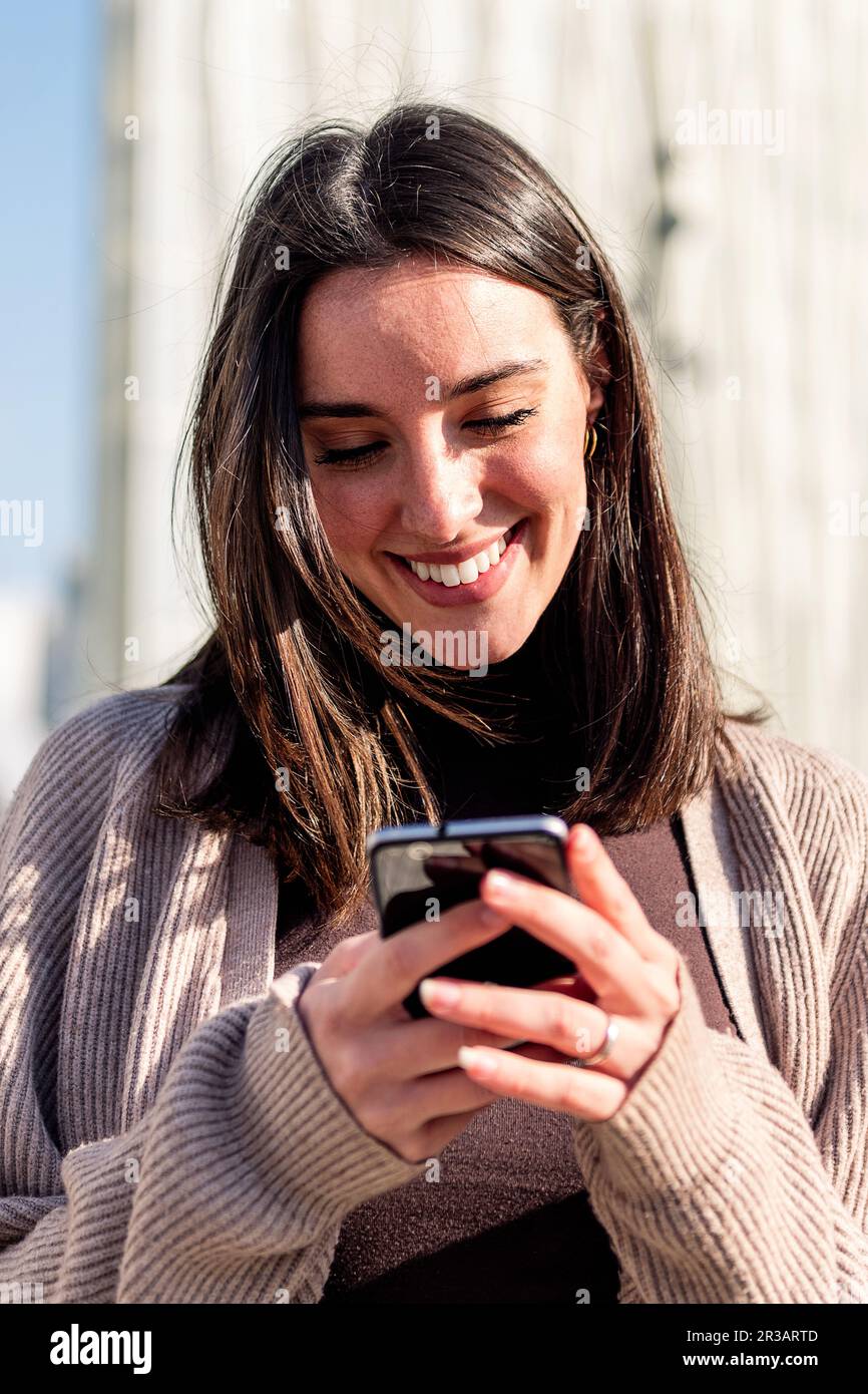 woman smiling happy while texting on her phone Stock Photo - Alamy