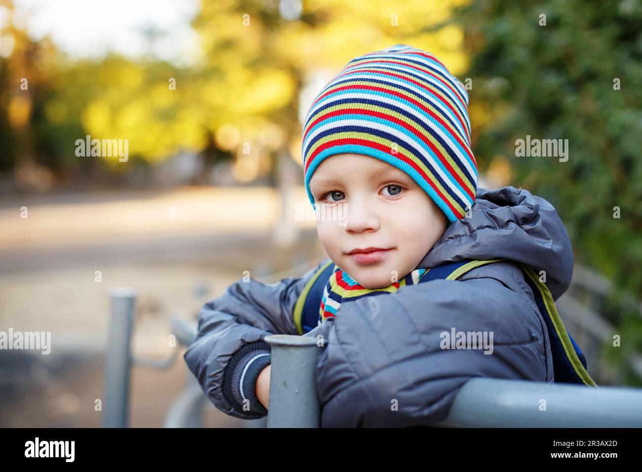 Beautiful little boy in bright striped hat and scarf outdoors Stock
