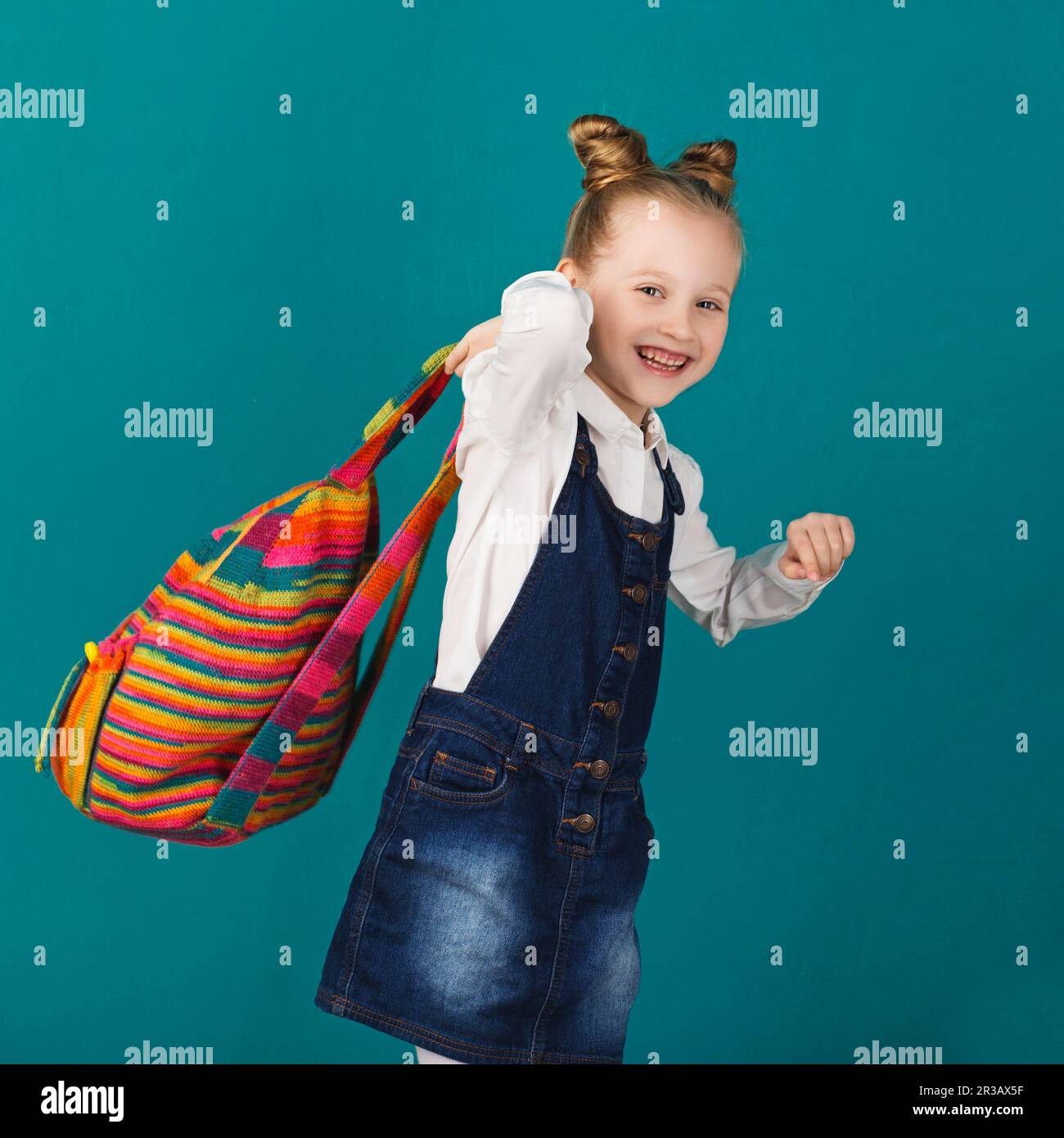 Funny smiling little girl with big backpack jumping and having fun