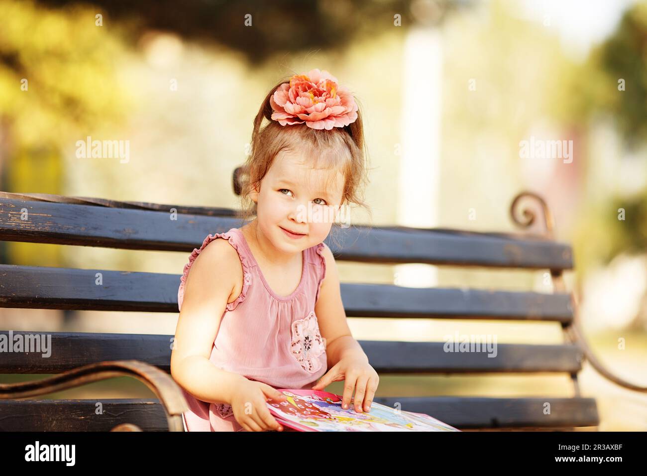 Portrait of a clever little girl reading a children's book on a park