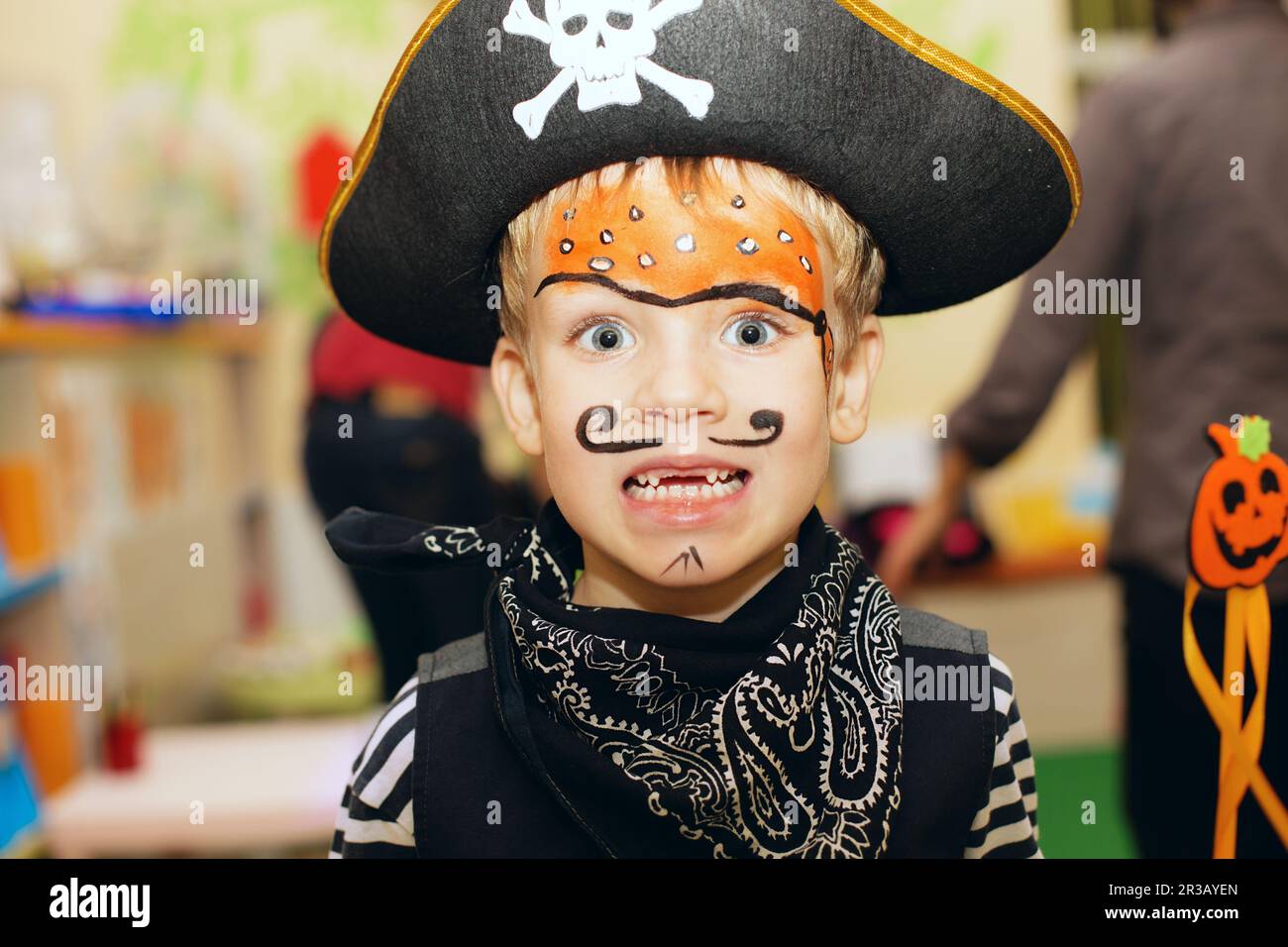 Halloween party. A little boy in a pirate costume and a makeup on his face is having a good time at Stock Photo