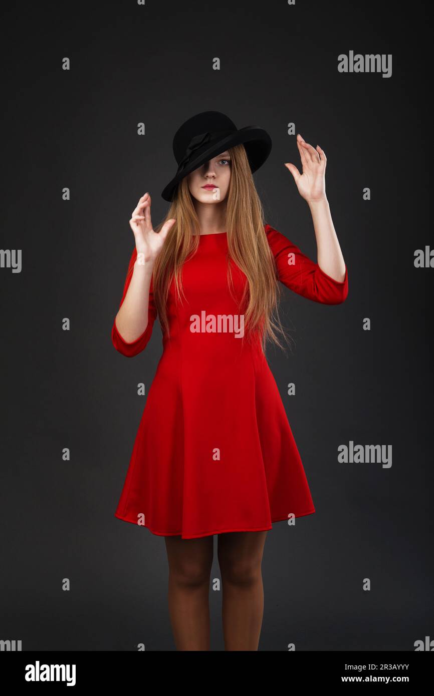 A beautiful girl in red dress and black felt hat Stock Photo - Alamy